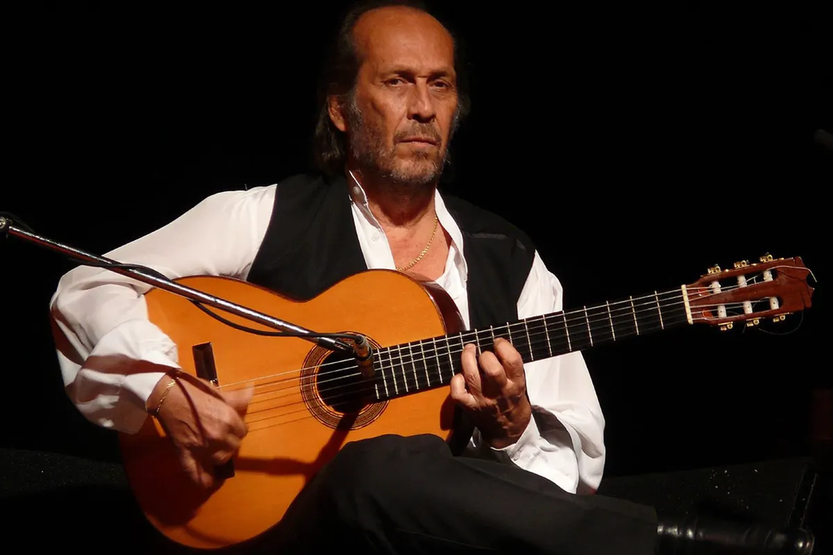 Paco de Lucía seated on stage with a flamenco guitar