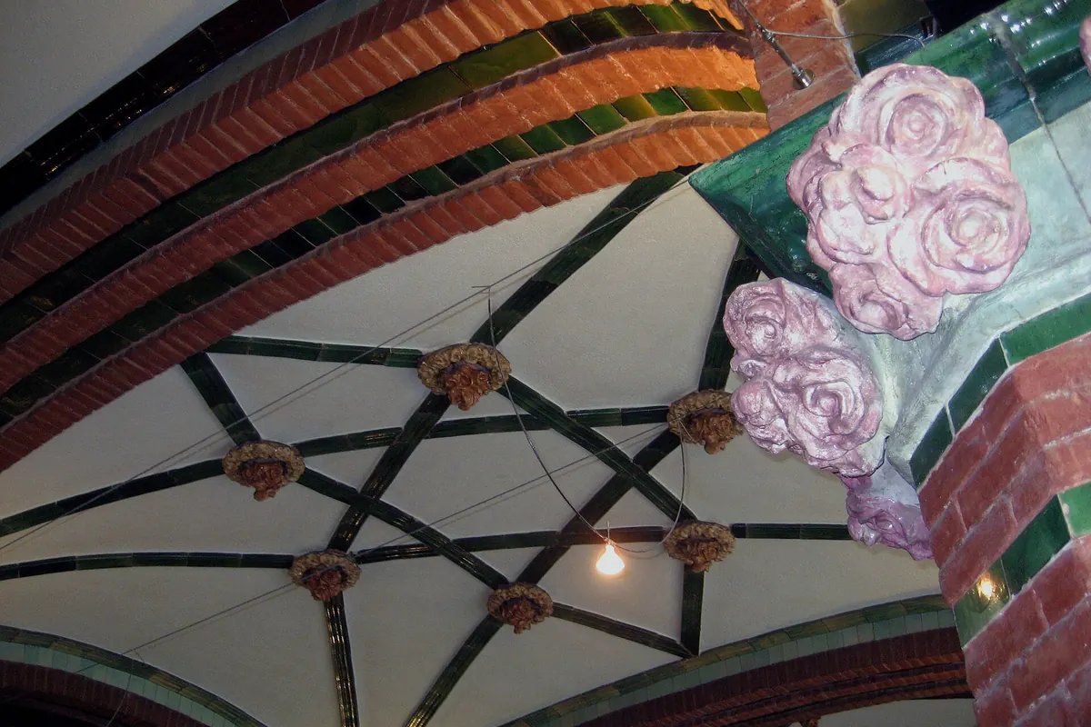 A brick and green-tile vault in the Palau with a star of tile ribs and pink ceramic roses in the corner.